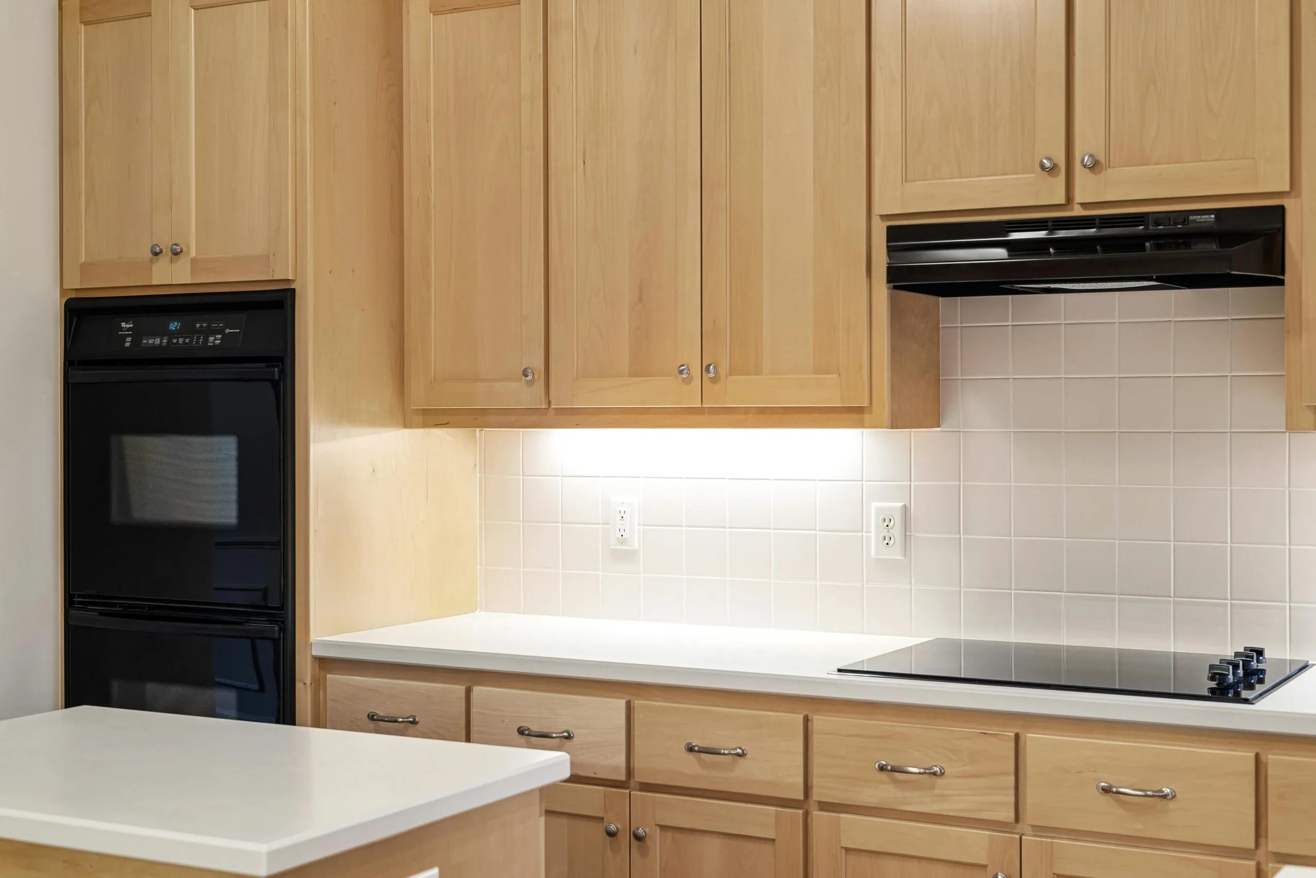 Kitchen with light wood cabinets, white countertops, and modern appliances